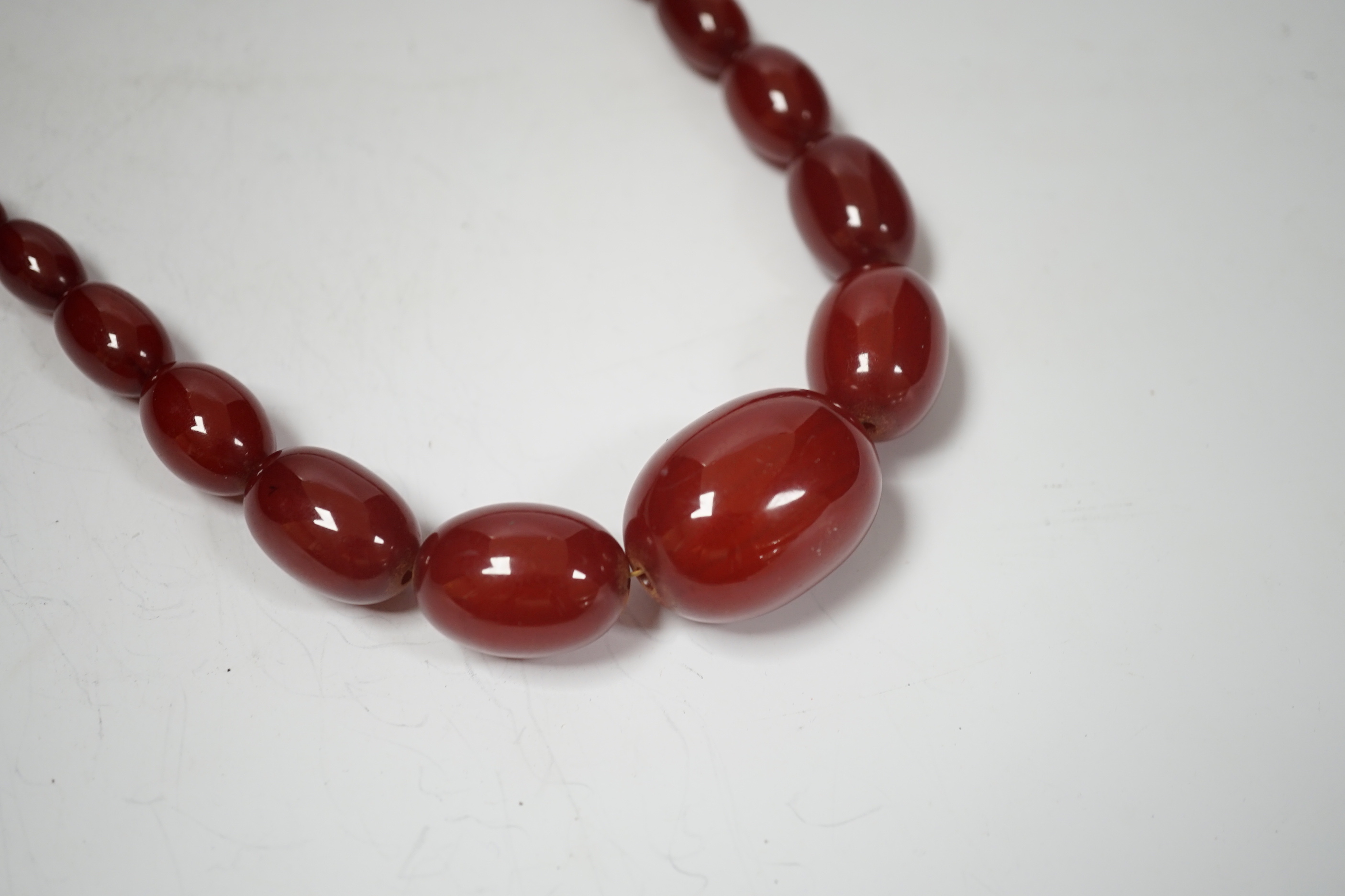 A single strand graduated oval simulated cherry amber bead necklace, 70cm, gross weight 63 grams.